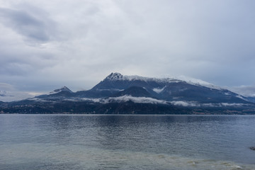 Fototapeta na wymiar Italy, Varenna, Lake Como, a body of water with a snowcap mountain in the background