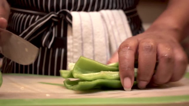 Woman slicing and chopping green chili peppers and scooping up, Close Up