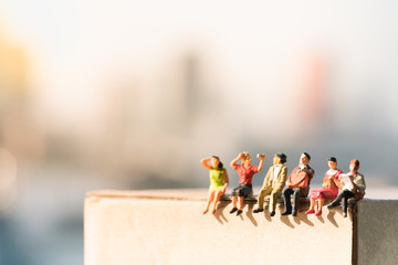 Miniature people: small figures sitting on paper box with city backgrounds using as business and social concepts.