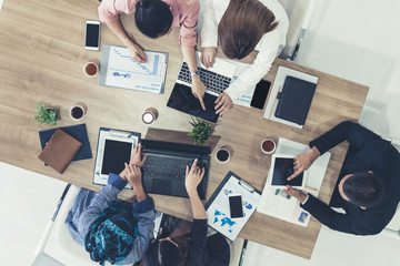Top view of businessman executive in group meeting with other businessmen and businesswomen in modern office with laptop computer, coffee and document on table. People corporate business team concept.