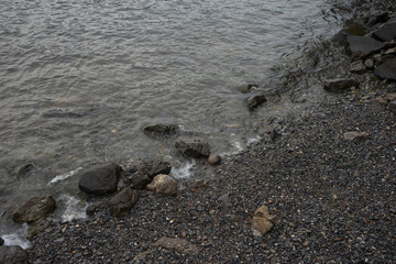 Italy, Varenna, Lake Como, a rocky beach next to a body of water