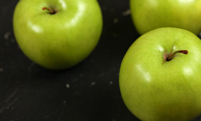 Close up photo, green apples on black board.