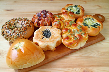 Assorted buns and pastries on wooden tray served on wooden table 