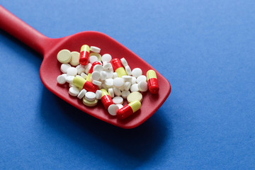 Medicine expenses. Various medicines and pills on red spoon with copy space