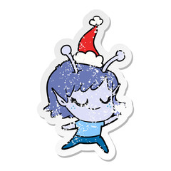 smiling alien girl distressed sticker cartoon of a wearing santa hat
