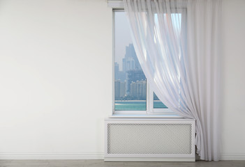 Beautiful view from new modern window with curtain in empty light room, space for text