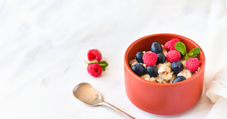 oatmeal with organic blueberries and raspberries, fresh orange juice and grapes. light background, selective focus and copy space, Breakfast concept. diet, healthy food