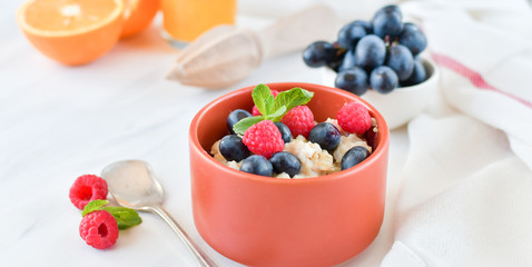 oatmeal with organic blueberries and raspberries, fresh orange juice and grapes. light background, selective focus and copy space, Breakfast concept. diet, healthy food