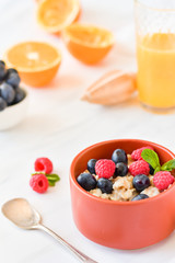 oatmeal with organic blueberries and raspberries, fresh orange juice and grapes. light background, selective focus and copy space, Breakfast concept. diet, healthy food