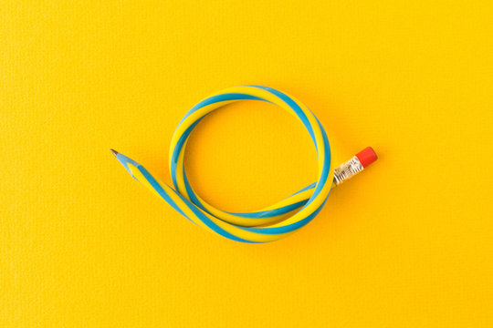 Flexible pencil . Isolated on yellow background. Bending pencil