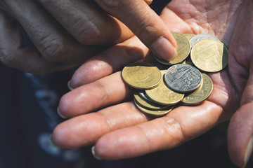 Fototapeta premium Close up hand holding coins for saving concept on dark background.