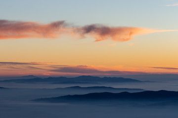 Beautifully colored sky at dusk, with mountains layers and mist between them