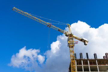 Fototapeta na wymiar Building construction site with tower crane against blue sky.