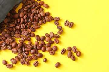 Coffee beans randomly scattered on yellow background.