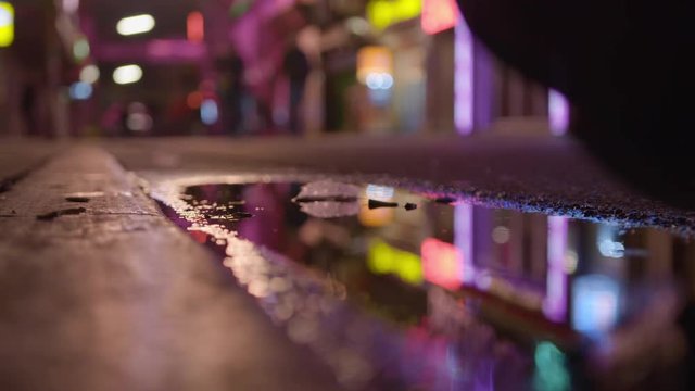 Man stepping into muddy puddle at night time in neon lit street Reeperbahn Hamburg St Pauli Grosse Freiheit Germany Red Light District Nightlife