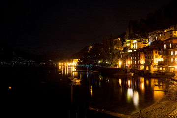 Italy, Varenna, Lake Como, a view of a city at night in front of a body of water