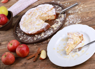 homemade apple pie - a piece of homemade apple pie on a plate with fresh apples and cinnamon sticks on a rustic wooden table