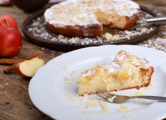 homemade apple pie - a piece of homemade apple pie on a plate with fresh apples and cinnamon sticks on a rustic wooden table
