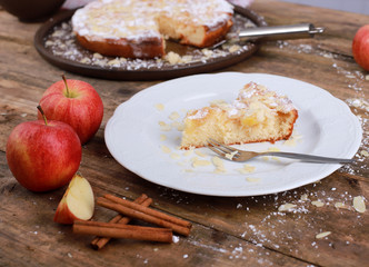 homemade apple pie - a piece of homemade apple pie on a plate with fresh apples and cinnamon sticks on a rustic wooden table