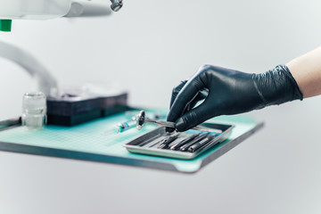 Close-up of dentist's hands in gloves choosing dental tool.