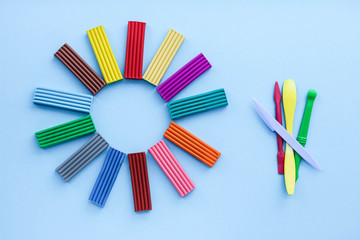 multi-colored plasticine is a material for creativity with children. modeling-the development of fine motor skills. on a blue background, top view.