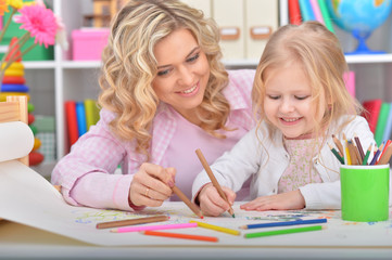 Portrait of little girl and mother drawing with pencils