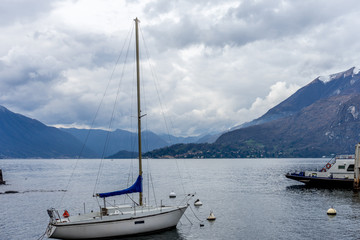 Italy, Varenna, Lake Como, a small boat in a body of water with a mountain in the background