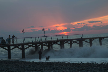 over Batumi beach Jetty, as powerful waves roll in, and a very colorful sky is reflected on the beach. sunset on the city embankment