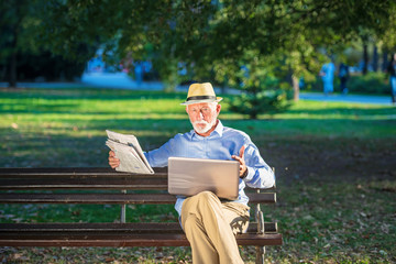 Senior man using laptop computer at rest in the park outdoors