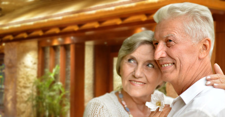 Portrait of happy senior couple hugging against blurred hotel interior background