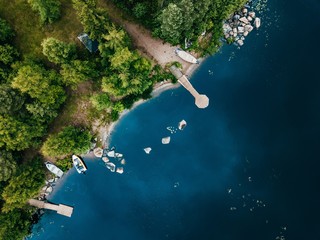 Aerial view of wooden cottage in green forest by the blue lake in rural summer Finland