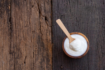 Natural homemade plain organic yogurt in wooden bowl and wood spoon on wood texture background