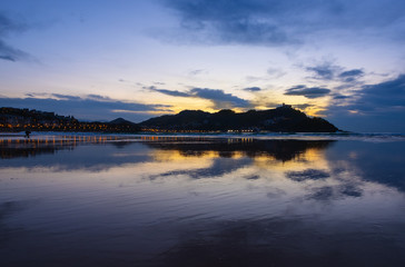 Lights of the city and Mount Igueldo are reflected in the beach of La Concha city of Donostia