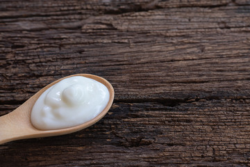 Natural homemade plain organic yogurt in wood spoon on wood texture background