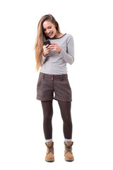 Cheerful excited young stylish woman typing or reading messages on mobile phone. Full body isolated on white background. 