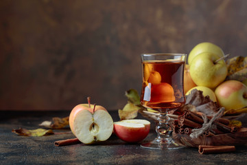 Glass of apple juice or cider with juicy apples and cinnamon sticks.