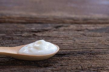 Natural homemade plain organic yogurt in wood spoon on wood texture background