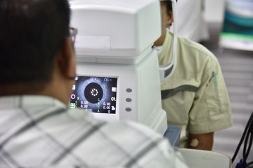 Man looking at refractometer eye test machine in ophthalmology.