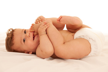 Hapy baby boy in playing on bed isolated over white