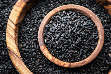 Black sesame seeds in the wooden bowl. Top view.