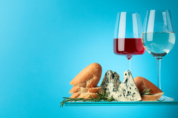 Blue cheese with bread, wine and rosemary on a blue background.