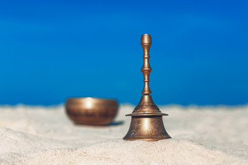Bell and singing bowl on the sand. Musical instruments  on the beach
