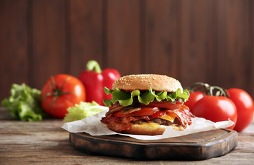 Tasty burger with bacon on wooden table. Space for text
