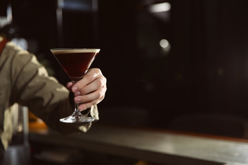 Barman holding espresso martini cocktail in pub, closeup. Space for text