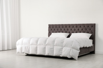 Comfortable bed with new mattress near wall in room. Healthy sleep