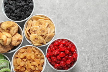 Bowls of different dried fruits on grey background, top view with space for text. Healthy food