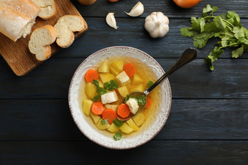 Flat lay composition with fresh homemade chicken soup on wooden background, top view