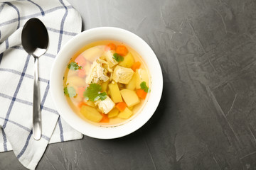Homemade chicken soup served on grey table, top view with space for text