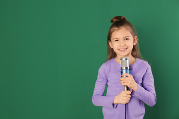 Cute funny girl with microphone on color background. Space for text