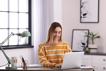 Teenage girl using laptop at table in her room
